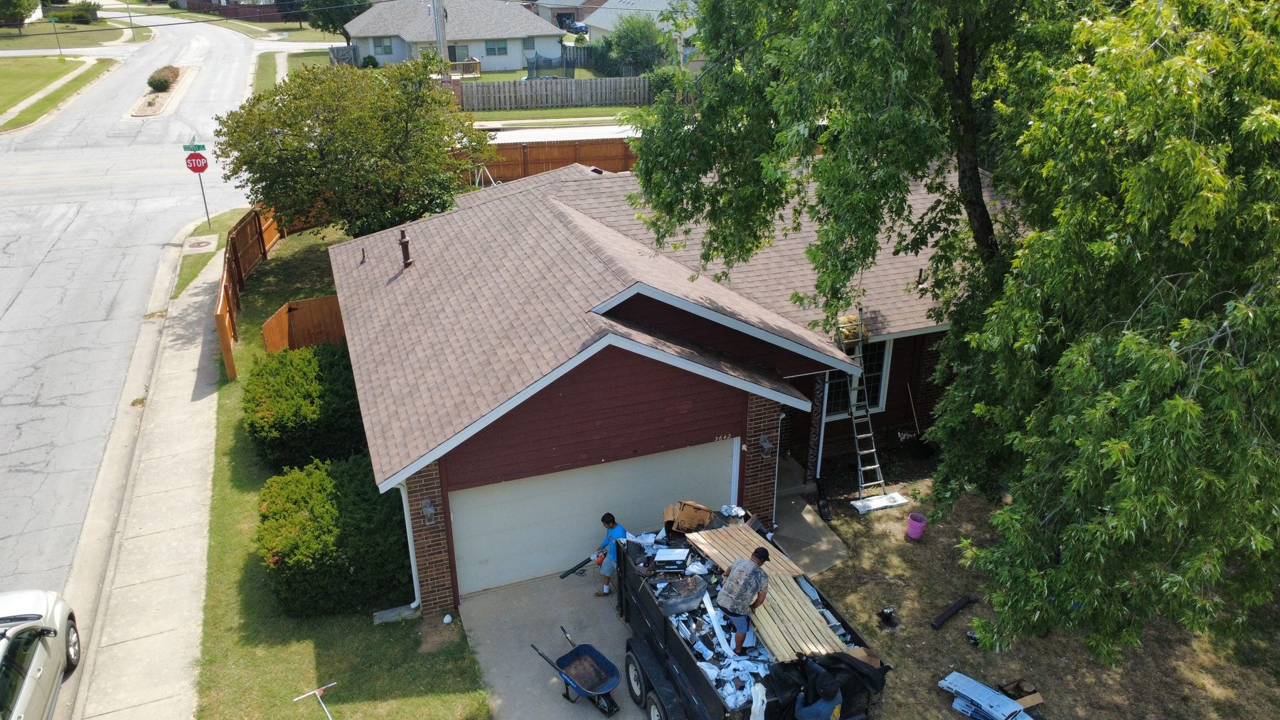 Roof replacement in progress with the dump trailer at the curb